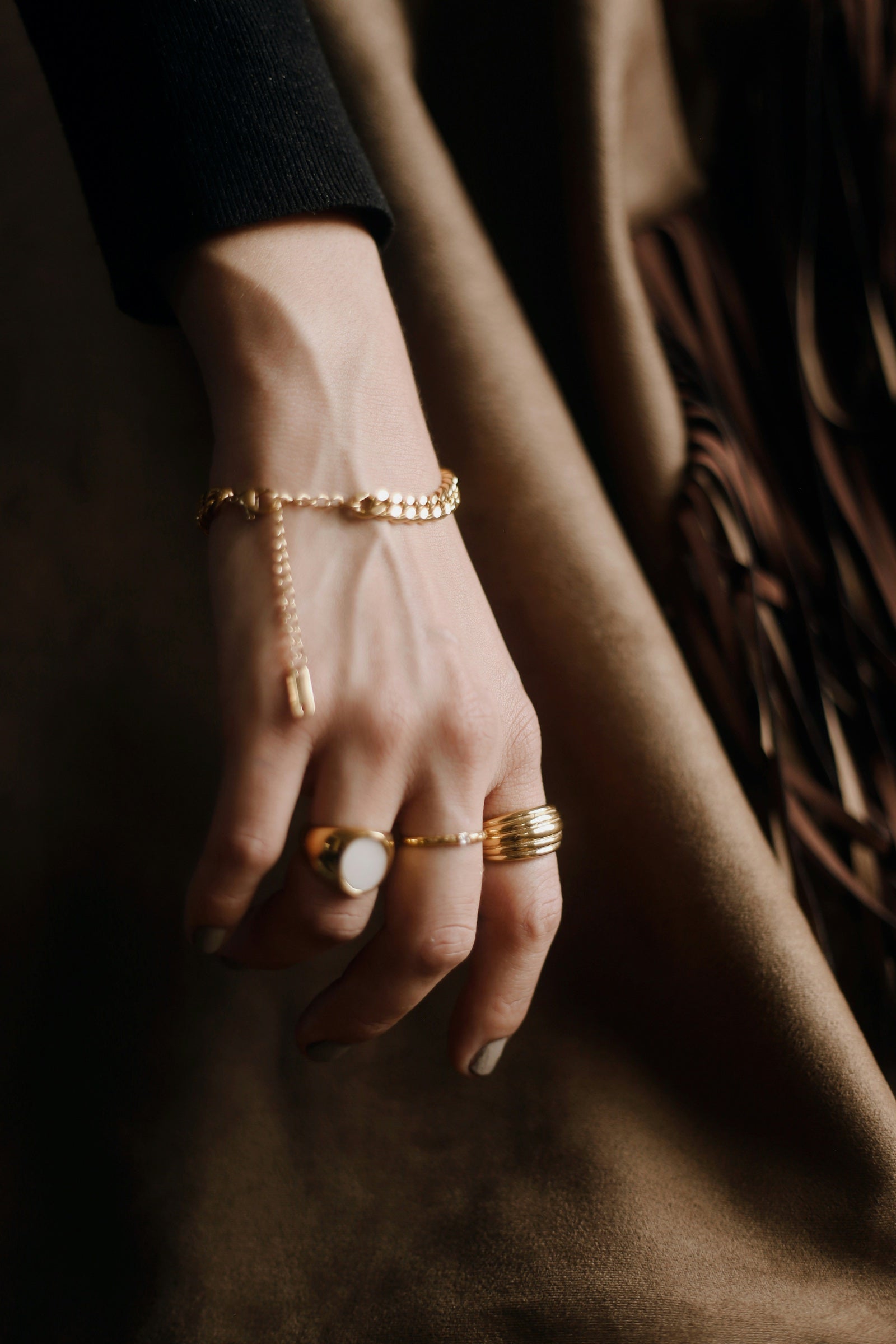 Gold rings and a chain bracelet worn on the hand