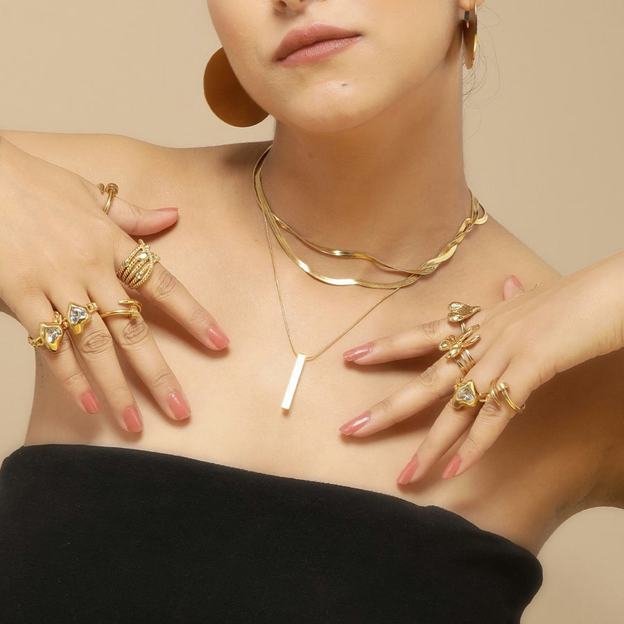 Layered gold chain necklaces worn with stacked gold rings