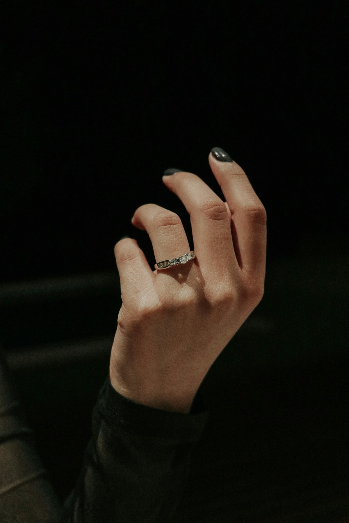 A hand wearing a gold band set with five round diamonds